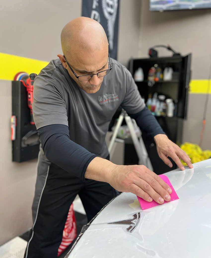 Xtreme Xcellence Detailing technician applying paint protection film to a vehicle hood